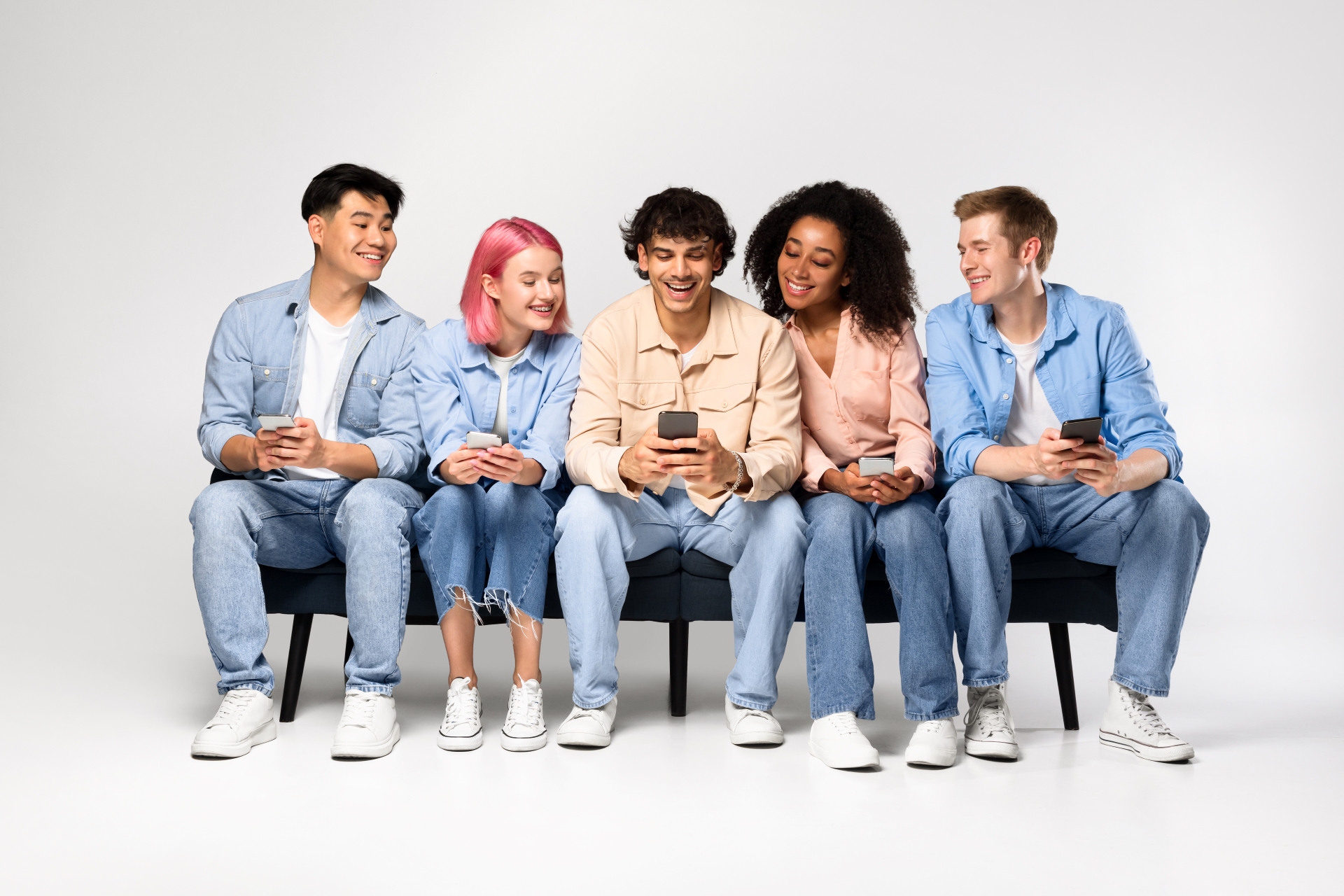 Group of five diverse friends smiling and looking at a smartphone together.