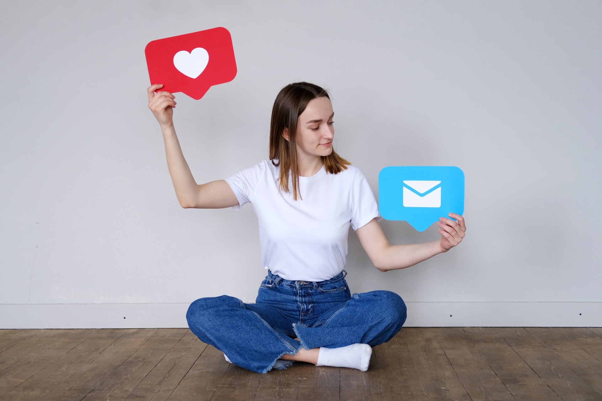 Young woman holding up a love heart icon and a message bubble icon.