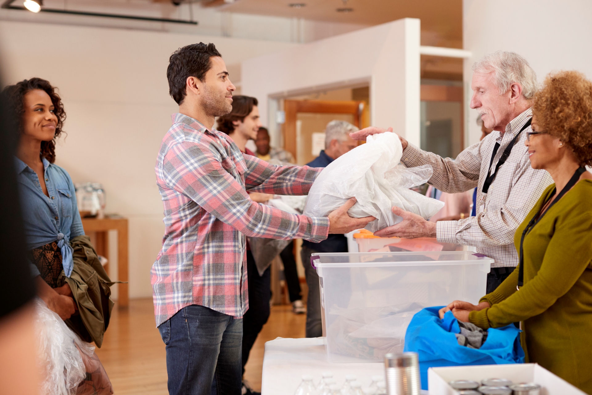 Man donating items to a senior volunteer at a charity event.