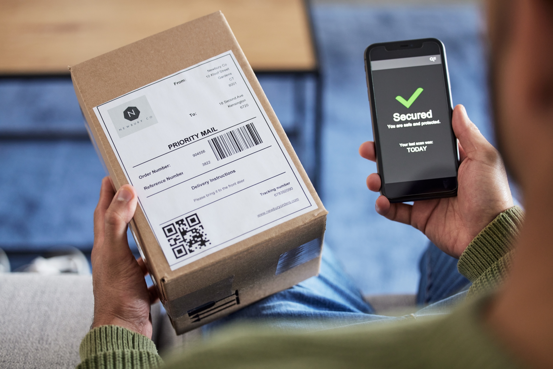 Person holding a packaged parcel and a smartphone displaying a 'Secured' confirmation message.